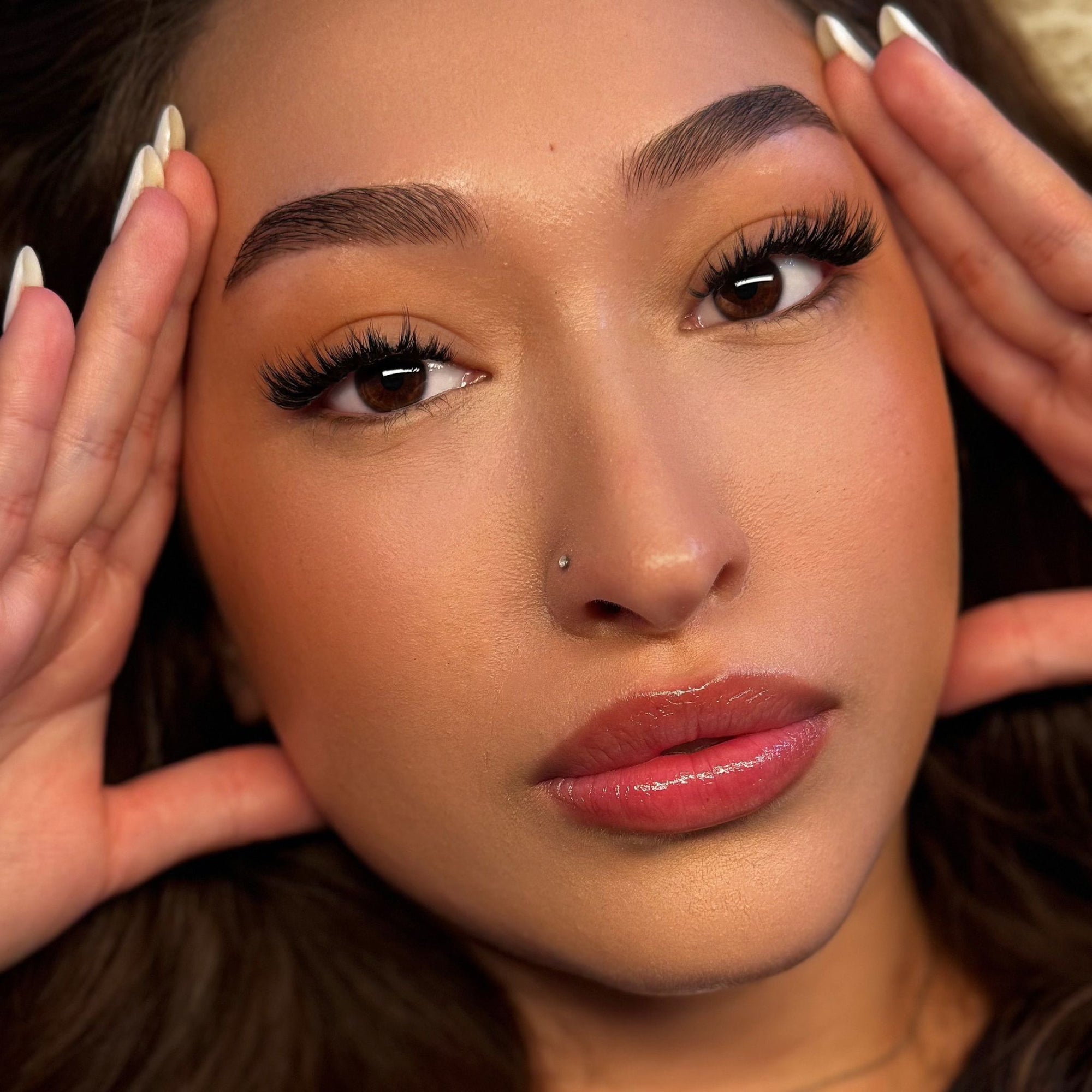 Close-up of a person with hands on their face signature false eyelash curls